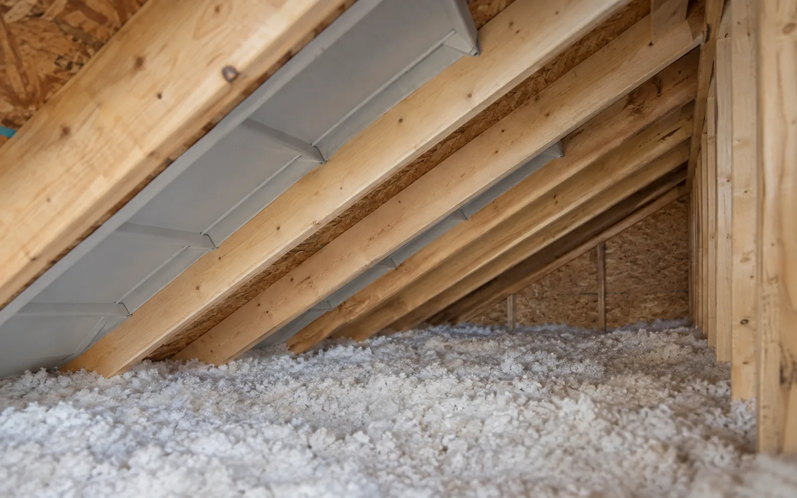 A rafter-bay baffle above the loose-fill insulation near the roof edge.