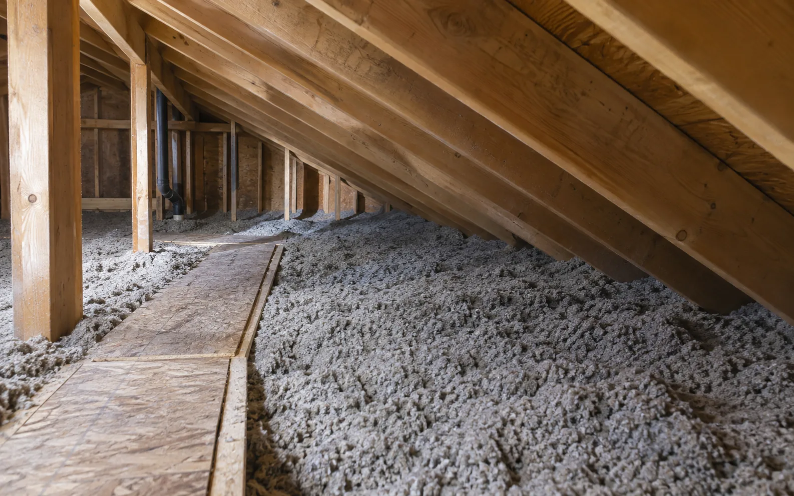 Grey loose-fill insulation beneath a low roof with an offset attic access path.