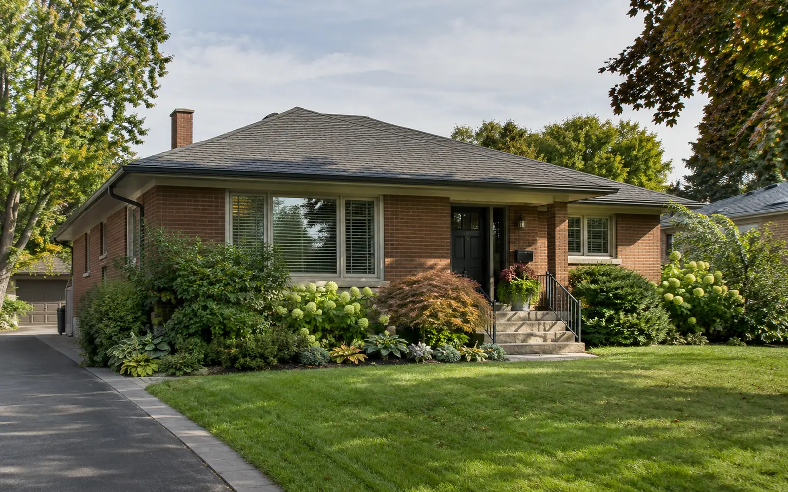 A brick bungalow with a broad low roof and mature landscaping.