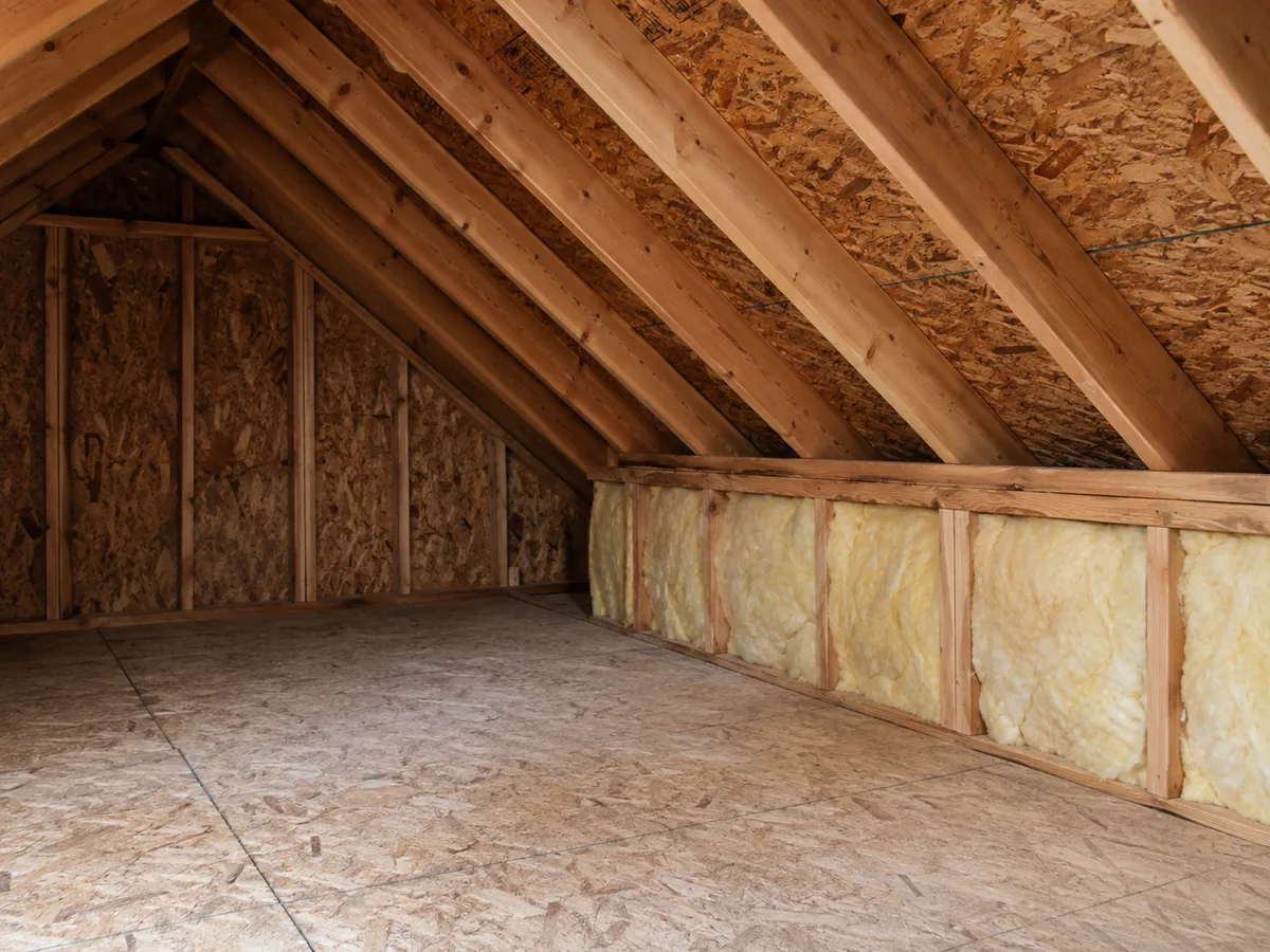 A partial attic with a short insulated wall beneath a sloping roof.